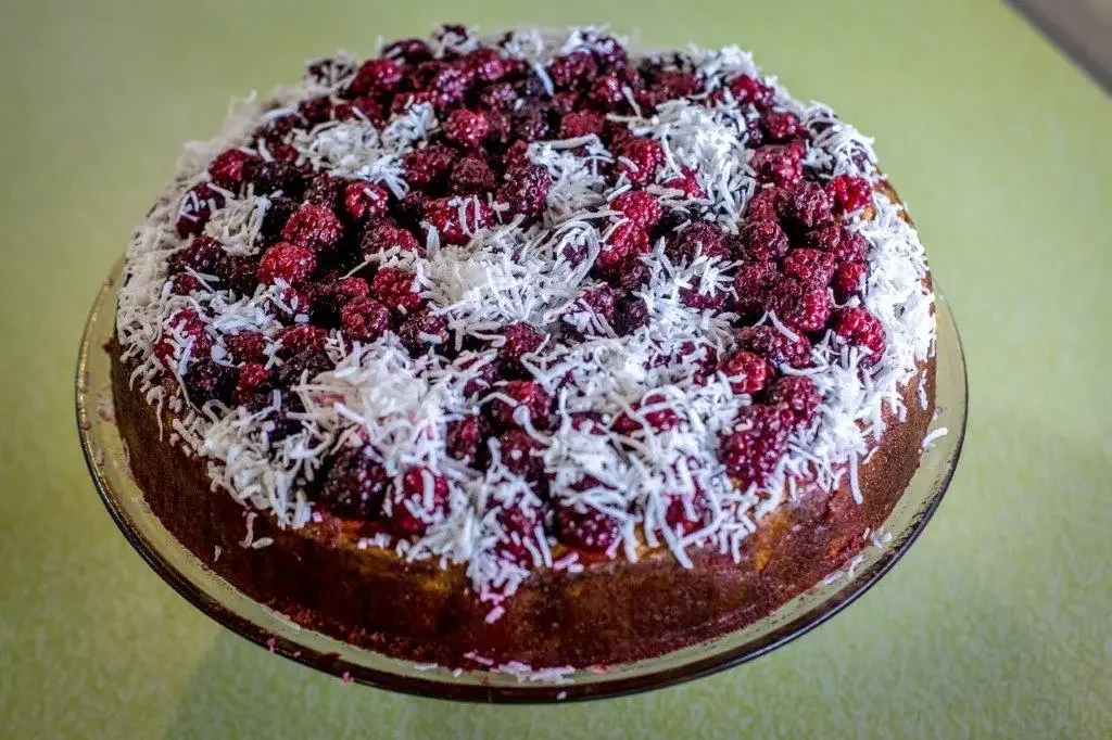 Round cake topped with raspberries and shredded coconut