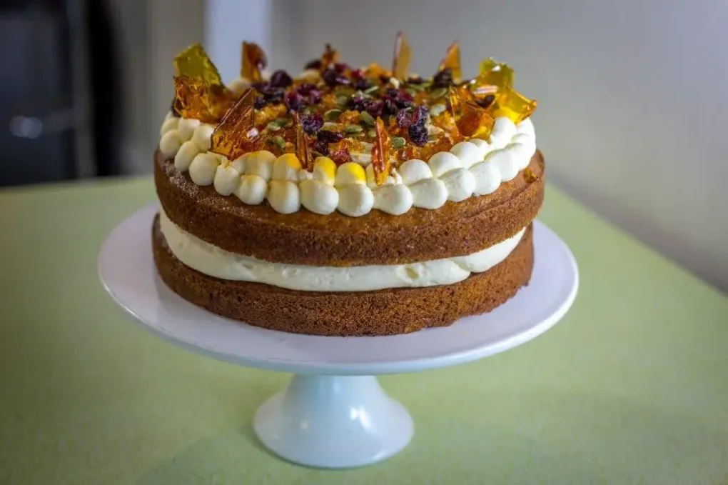 Layered sponge cake topped with cream, toffee shards, cranberries and pistachios
